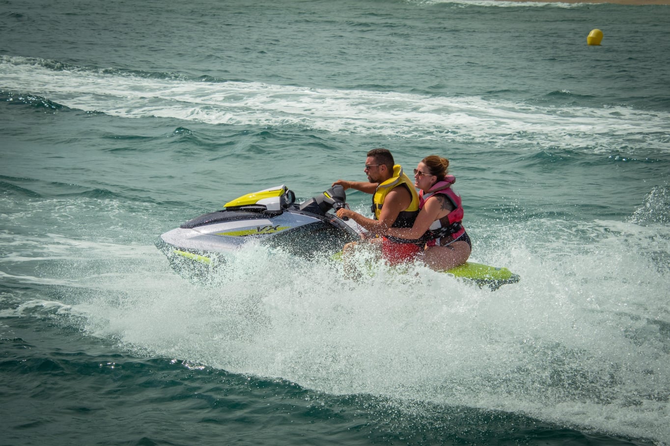 man and woman riding on a jet ski in the ocean